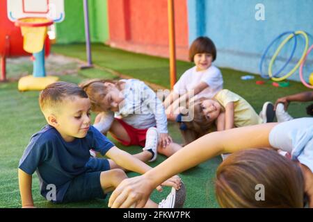 Gruppo di bambini che fanno ginnastica insieme in assistenza diurna o prescolare Foto Stock