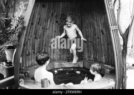 Ragazzi in una vasca calda rustica di legno Medstead, Hampshire, Inghilterra, Regno Unito. Foto Stock