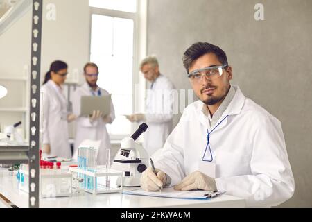 Ritratto di uomo scienziato che lavora in laboratorio facendo conclusione esperimento Foto Stock