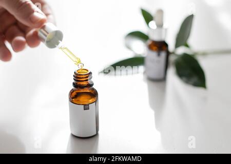 Pipettare con una goccia di olio essenziale e una bottiglia in mano. Bellezza, concetto di cosmetica naturale. Medicina alternativa Foto Stock