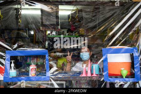 Una donna che indossa una maschera facciale posa attraverso un foglio di plastica di fronte al suo negozio lungo la linea ferroviaria.Bangkok città abitanti che vivono lungo la linea ferroviaria. La ferrovia di Stato della Thailandia (SRT) viaggia dalla stazione centrale di Bangkok a Hua Lamphong ad est della capitale e si collega a Chachoengsao, 82 km da Bangkok lungo questa linea. Foto Stock