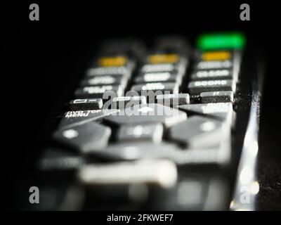 Messa a fuoco selettiva del telecomando con diversi pulsanti per Il televisore su sfondo nero Foto Stock