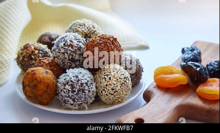 primo piano delle palle energetiche. Alimenti grezzi, vegani, sani con noci, semi di cia, semi di sesamo, lino, fiocchi di cocco e frutta secca, prugne e albicocca secca Foto Stock