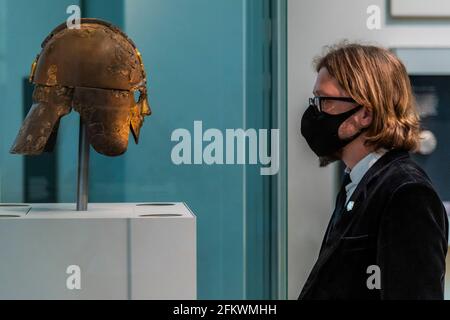 Londra, Regno Unito. 4 maggio 2021. Jim Peters, responsabile della collezione: Care and Access, con l'iconico casco in ferro ornato - i tesori di Sutton Hoo al British Museum. Hanno presentato nel film di successo The Dig Starring Ralph Fiennes e Carey Mulligan, non sono stati visti dal pubblico dal Museo chiuso per la prima volta nel marzo 2020 a causa della pandemia di Coronavirus. Credit: Guy Bell/Alamy Live News Foto Stock