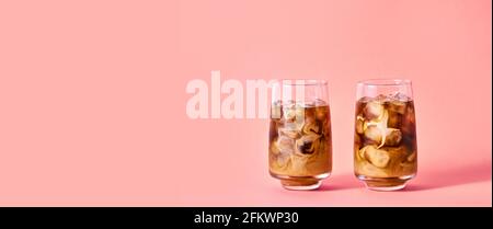 Caffè ghiacciato con latte in bicchieri da calice su sfondo rosa. Bevanda estiva rinfrescante di concetto. Foto Stock