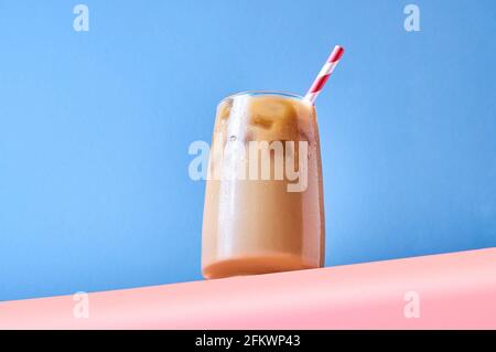 Caffè ghiacciato con latte in calici al tavolo rosa e sfondo blu. Hero View alla moda. Orientamento orizzontale. Foto Stock