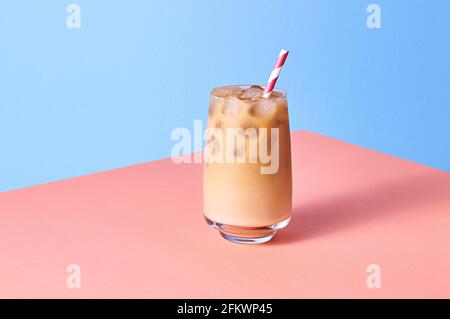 Caffè ghiacciato con latte in calici al tavolo rosa e sfondo blu. Orientamento orizzontale isometrico. Foto Stock