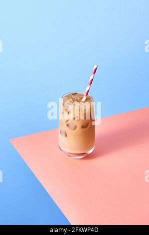 Caffè ghiacciato con latte in calici al tavolo rosa e sfondo blu. Orientamento verticale isometrico. Foto Stock