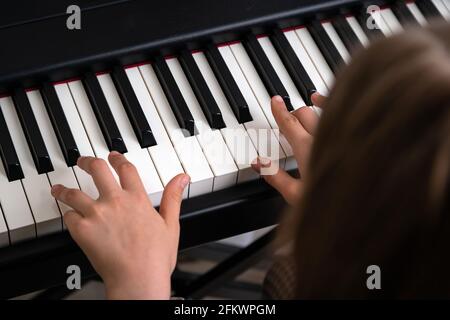 Primo piano di un adolescente che suona il pianoforte in uno studio di musica di casa. Ragazza che ha corso online e che pratica sul pianoforte elettrico moderno Foto Stock