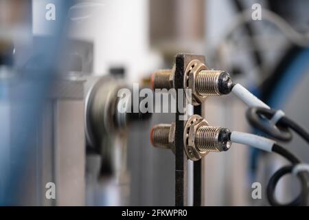 Primo piano del sensore laser di una macchina di fabbrica. Linea di assemblaggio automatizzata. Foto Stock