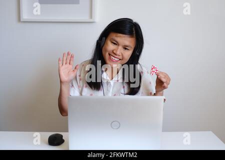 Filippino filippina Asiatica donna o ragazza insegnante che lavora seduto di fronte a una scrivania bianca e computer argento, insegnando una lezione online su Internet Foto Stock
