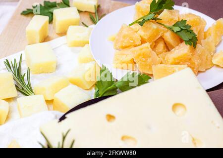 Varietà di parmigiano e maasdam pezzi di formaggio in cucina su sfondo chiaro. Foto Stock