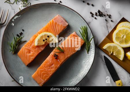 due filetti di salmone serviti su un piatto con limone e. rosmarino sul tavolo Foto Stock