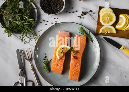 Vista aerea di due filetti di salmone serviti su un piatto con limone e rosmarino sulla tavola Foto Stock