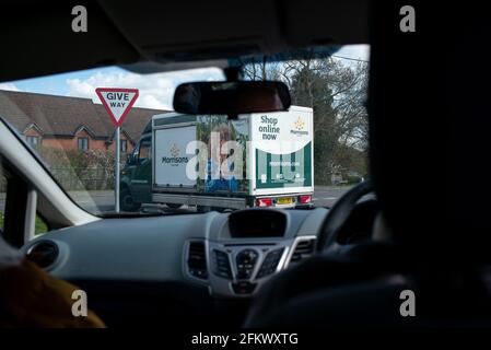 Acquista online il pulmino Morrisons visto dal punto di vista di un passeggero in un'auto che viaggia lungo una strada del villaggio. Foto Stock