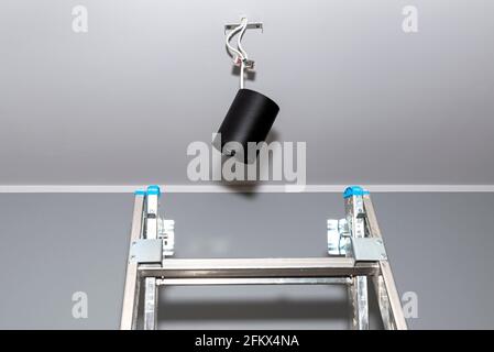 Moderna illuminazione a LED a forma di tubo, rivestita di vernice nera opaca, appesa ai cavi con un connettore rapido. Foto Stock