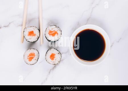 Sashimi classici con pesce salmone, salsa di soia e tristini su sfondo bianco del tavolo in marmo - rotolo di sushi maki, nori maki, futomaki. Cibo asiatico Foto Stock