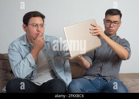 coppia gay con laptop, comunicazione online, problemi tecnologici, istruzione Foto Stock