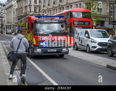 Fire Engine on Emergency guida lungo Regent Street sul lato sbagliato della strada, dopo la coda del traffico, fermandosi un motociclista elettrico, Londra, Regno Unito. 4 maggio 2021 Foto Stock