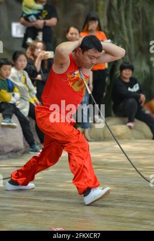 (NOTA PER LA REDAZIONE: L'immagine contiene contenuti grafici) durante la festa del giorno di maggio, gli artisti folk eseguono piercing della gola con lancia d'oro per i turisti nel parco ecologico di Fuyang. (Foto di Sheldon Cooper / SOPA Images/Sipa USA) Foto Stock