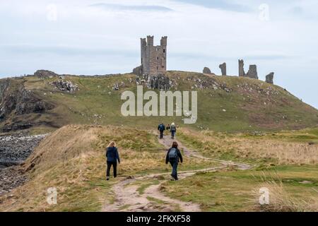 Craster, 26 aprile 2021: Camminatori vicino all'antico castello di Dunstanburgh Foto Stock