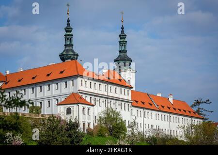 Praga, Repubblica Ceca - 3 maggio 2021: Vista del monastero di Strahov con facciata bianca e tetto rosso in una giornata di sole primavera con cielo blu. Due torri. Foto Stock