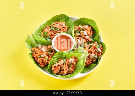Coppe di lattuga di carne tritata asiatiche su sfondo giallo. Vista ravvicinata Foto Stock
