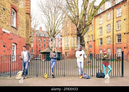 Gruppi di persone multirazziali e amici urbani che utilizzano uno smartphone vicino a Shoreditch Londra - concetto di stile di vita di dipendenza tecnologica con ragazzi annoiati e. ragazze Foto Stock