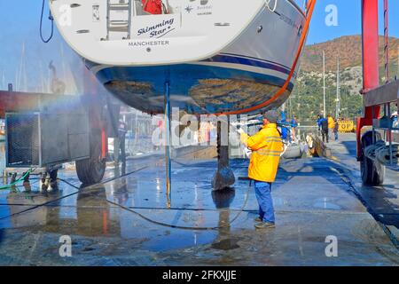 Yacht da crociera che viene sollevato e jet-lavata per rimuovere la incrostazione marina. Foto Stock