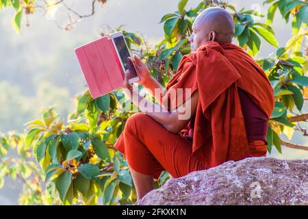 MANDALAY, MYANMAR - 3 DICEMBRE 2016: Monaco buddista con il suo computer tablet sulla collina di Mandalay, Myanmar Foto Stock