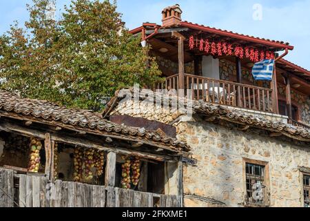 Peperoni, cipolle e una bandiera greca battenti, sui balconi delle case nel villaggio di pescatori di Psarades sul lago di Prespa, Macedonia, Gree del Nord Foto Stock