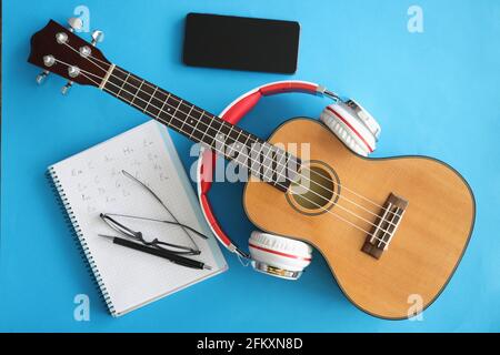 Chitarra con cuffie smartphone e notebook su sfondo blu Foto Stock