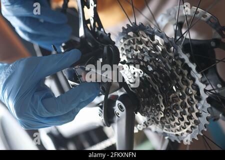 L'handyman con guanti ripara il closeup della cassetta posteriore della bicicletta Foto Stock