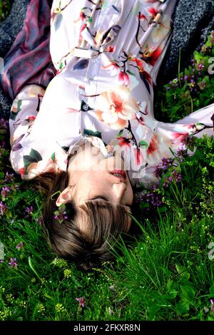 ritratto di bella ragazza giace in fiori sul campo Foto Stock