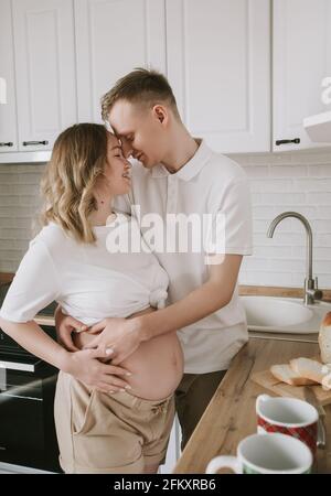 Donna incinta il taglio di cetriolo per una fresca insalata verde, femmina prepara una gustosa cena biologica a casa, nutrizione sana per la futura madre Foto Stock