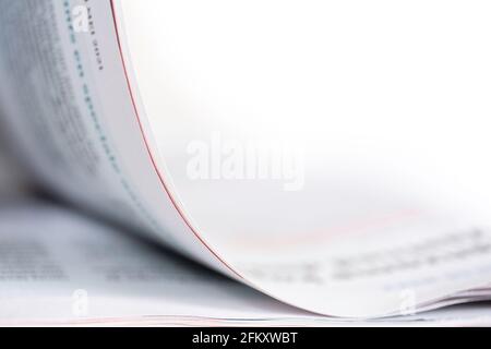 Pagina capovolta con un sottile bordo rosso di una rivista. Testo illeggibile, profondità di campo ridotta. Spazio di copia Foto Stock