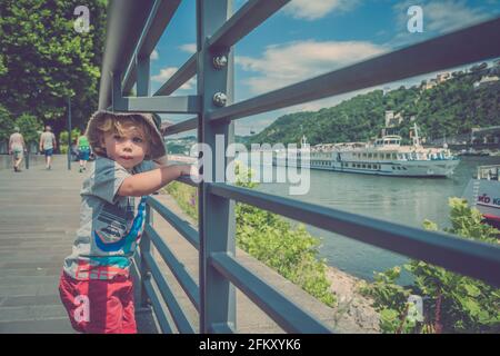 Giovane ragazzo che guarda le barche sul fiume Foto Stock