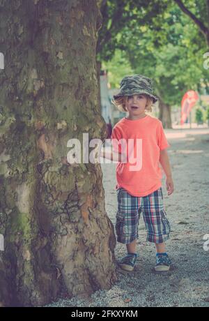 Ragazzo giovane che gioca sotto un albero Foto Stock