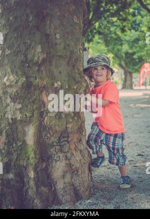 Ragazzo giovane che gioca sotto un albero Foto Stock