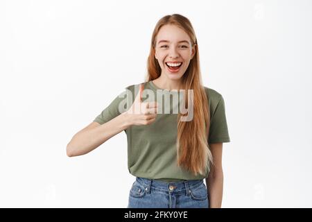 Allegra donna caucasica mostra i pollici e dire sì, sorridente soddisfatto, raccomandare società o marca, approvare e come qualcosa di buono, scelta di lode Foto Stock