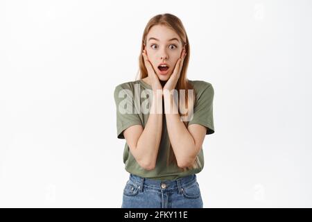 Immagine di ragazza sorpresa in awe, mascella goccia e gastping stupito, sentire le notizie impressionanti impressionanti, tenendo le mani sulla faccia, fissare a qualcosa unbelievable Foto Stock