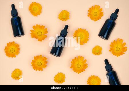 Fiori di Marigold. Flacone contagocce con olio marigolante. Spazio di copia. Disposizione piatta. Foto Stock