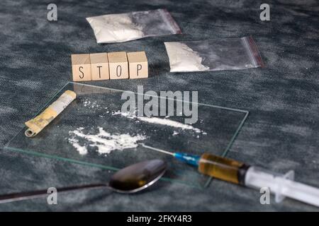Tossicodipendenza, linea di polvere bianca, cocaina, velocità o altri farmaci e siringa con eroina e IL testo STOP. Spazzatura, dipendenza, concetto di droga sfondo Foto Stock