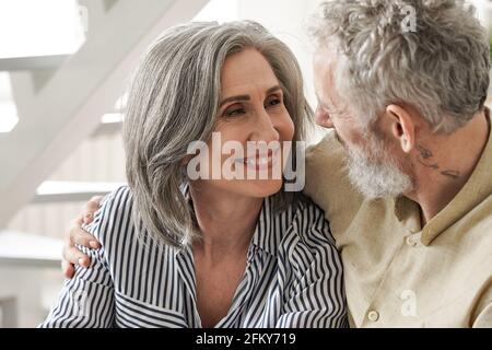 Felice moglie adulta matura guardando affettuoso marito anziano godendo di parlare. Foto Stock