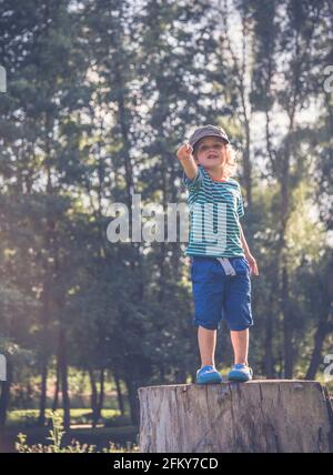 Young Boy si trovava su un tronco d'albero facendo espressioni diverse Foto Stock