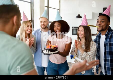 Gruppo di amici felici e diversi che hanno festeggiato il compleanno, congratulandosi con il loro collega studente, godendo di festa a casa Foto Stock