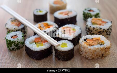 Set di sushi di maki con bastoncini di chopsticks su sfondo di legno per menu Foto Stock