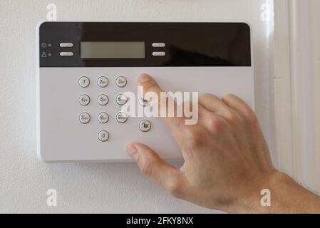 Uomo che imposta un allarme in un appartamento Foto Stock