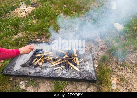 Primo piano vista di uomo che inizia il fuoco sul camino esterno. Foto Stock