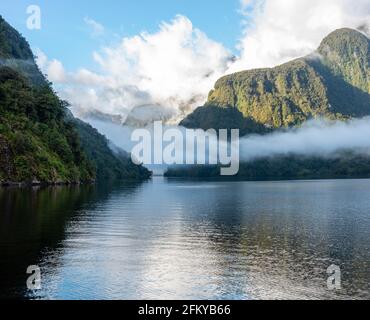 Una nuova mattina che si innamora a Doutful Sound, nuvole che pendono in basso nelle montagne, Isola del Sud della Nuova Zelanda Foto Stock